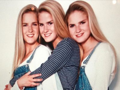 Dahm Triplets are posing by leaning their head on one another and the middle one is hugging the first one.